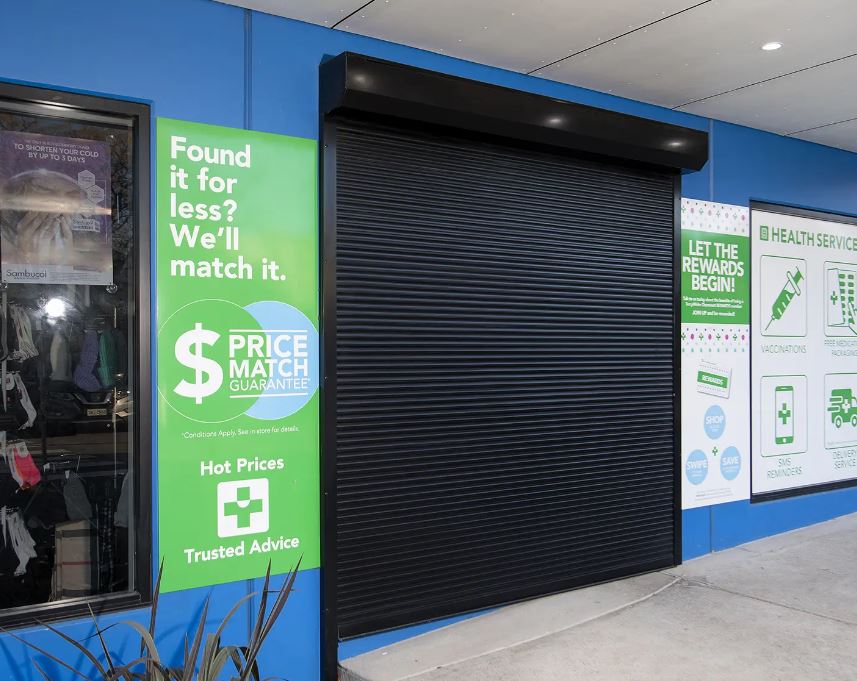 Black commercial roller shutter installed over a health services shopfront for security and break-in prevention.